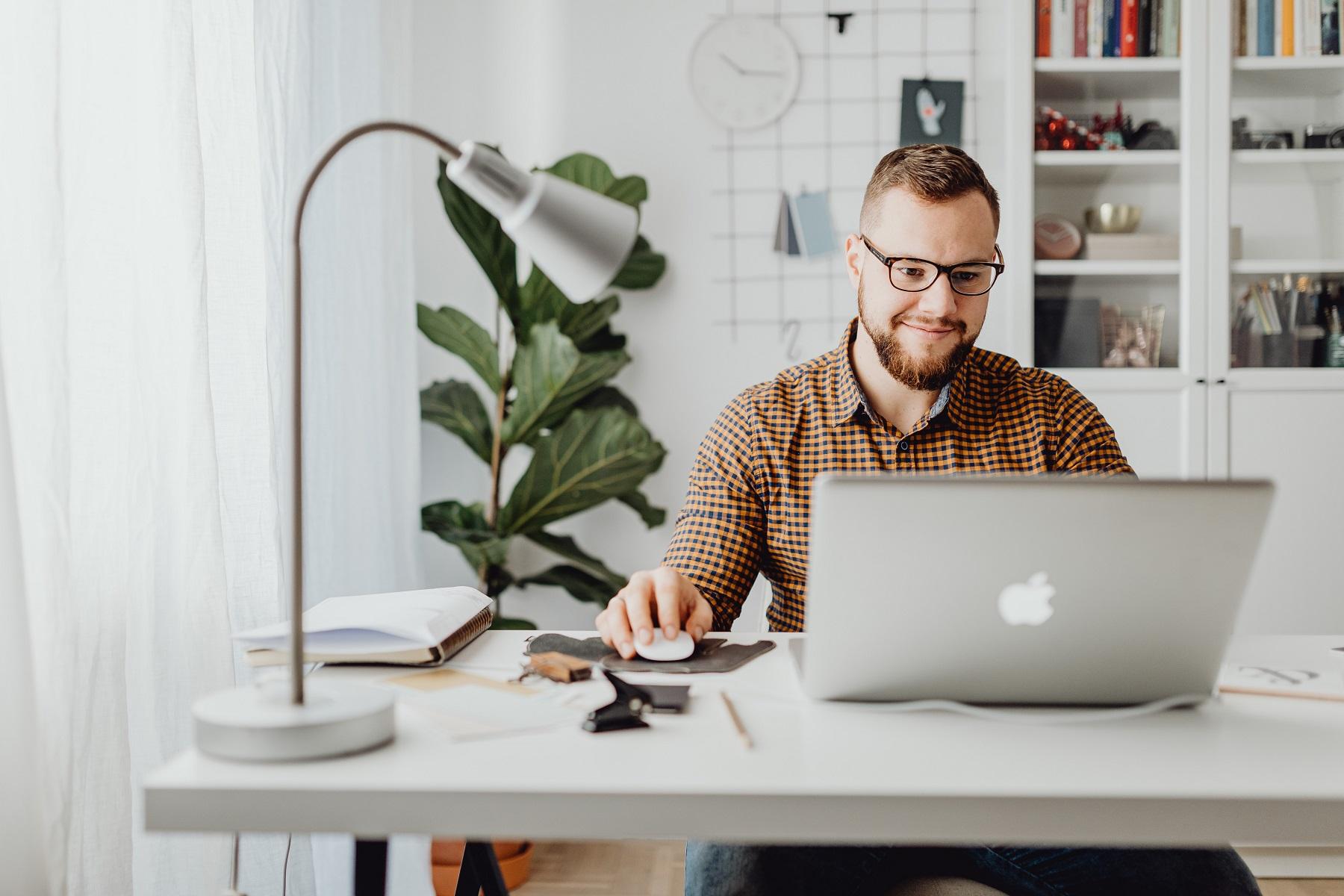 Photo of a man working at a laptop in a home office.