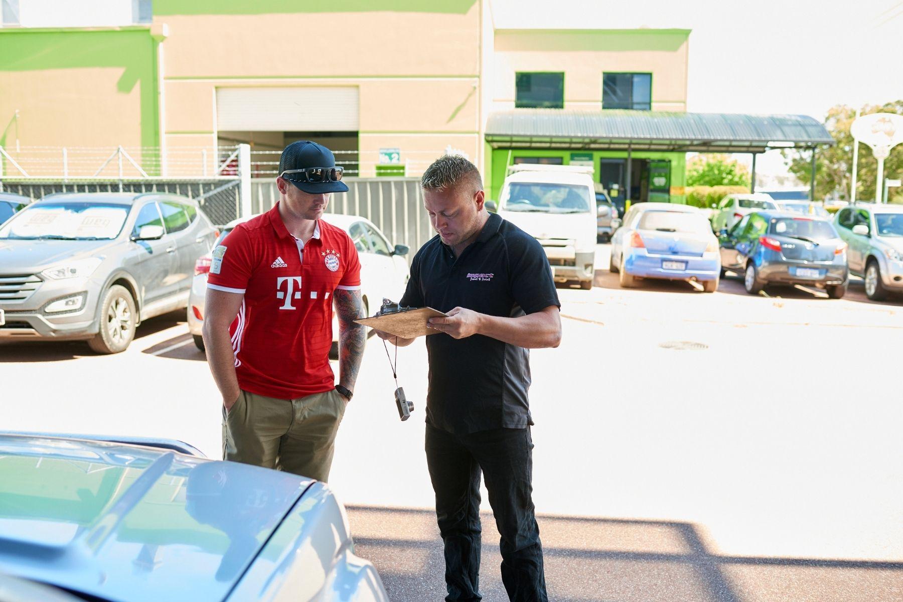 Photo of a panel beater speaking to a customer.