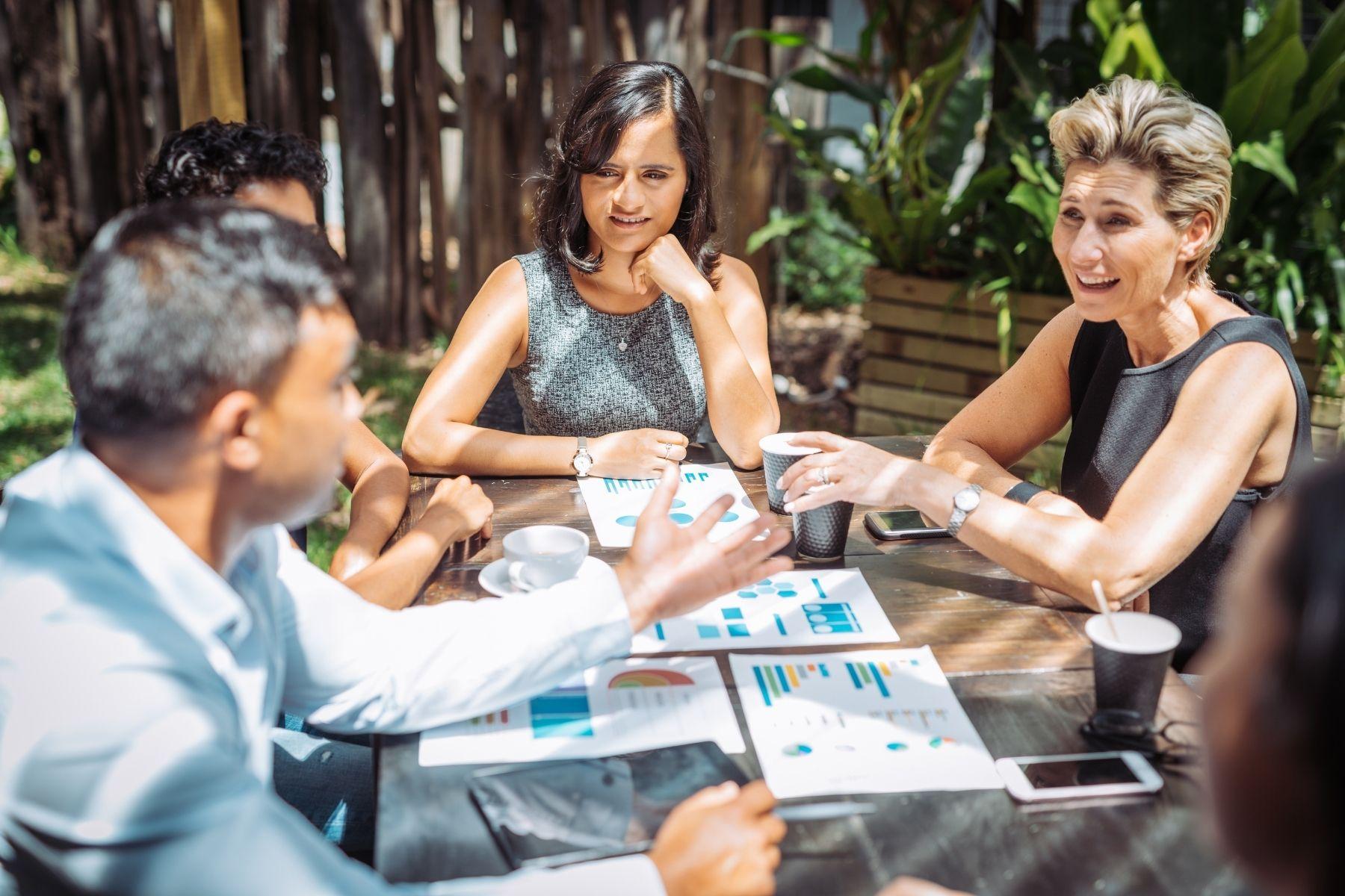 A photo of a group of people having a meeting outdoors.