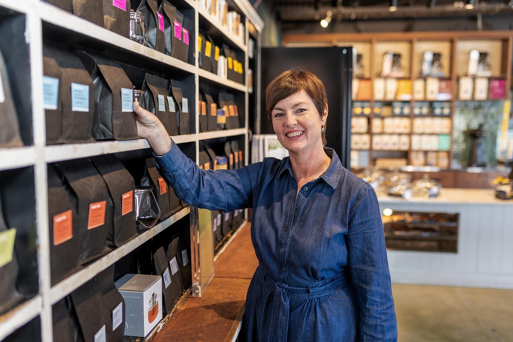 Photo of a female business owner standing in her store front.