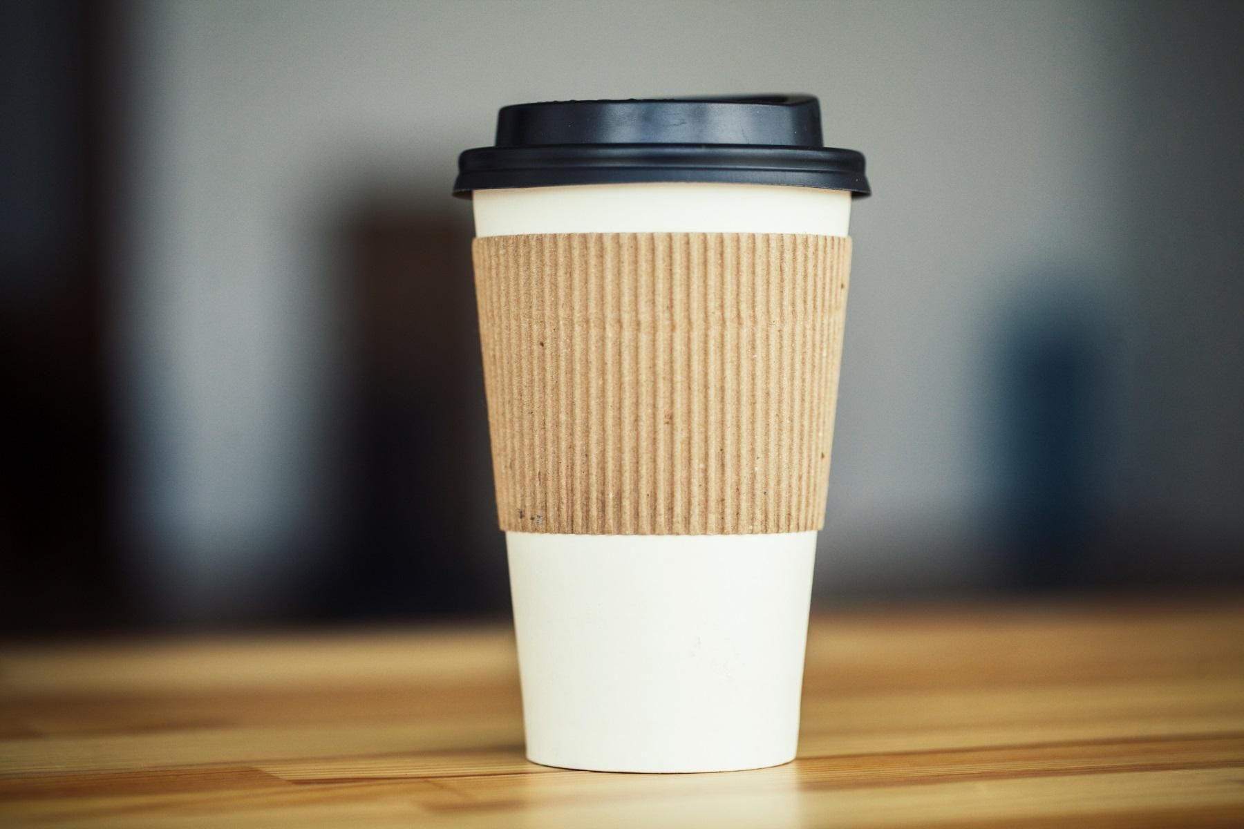 Photo of a takeaway coffee cup on a wooden bench.