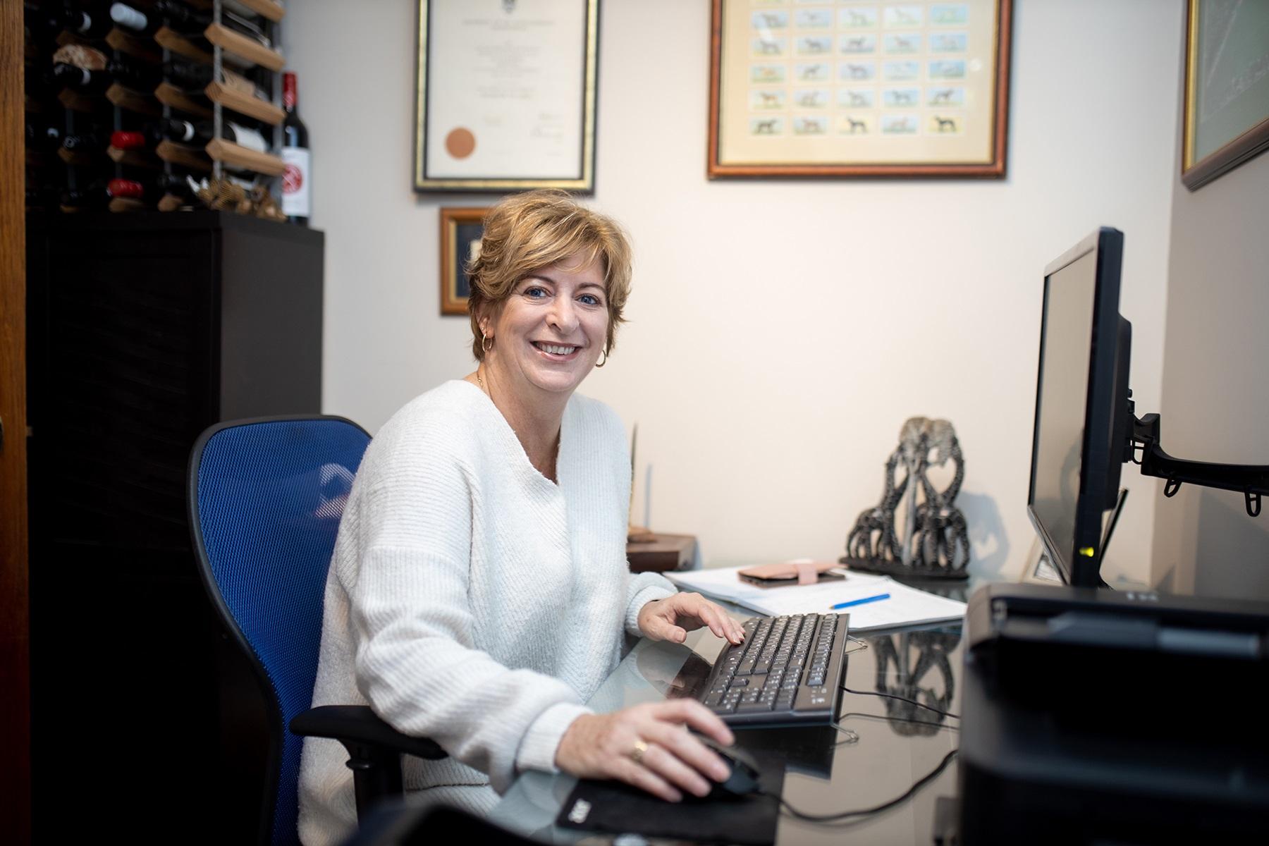 Photo of a woman working at a computer in a home office.