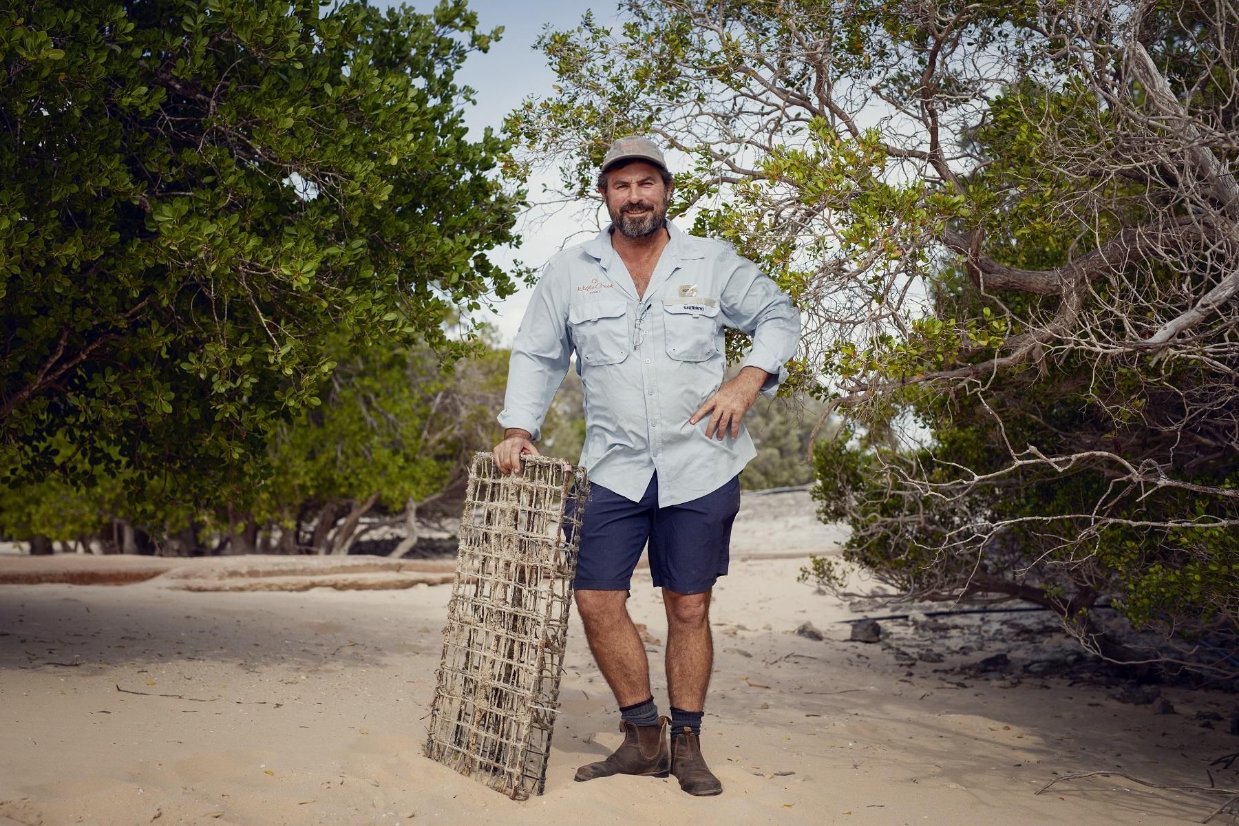 Image of a man standing on sand looking at the camera