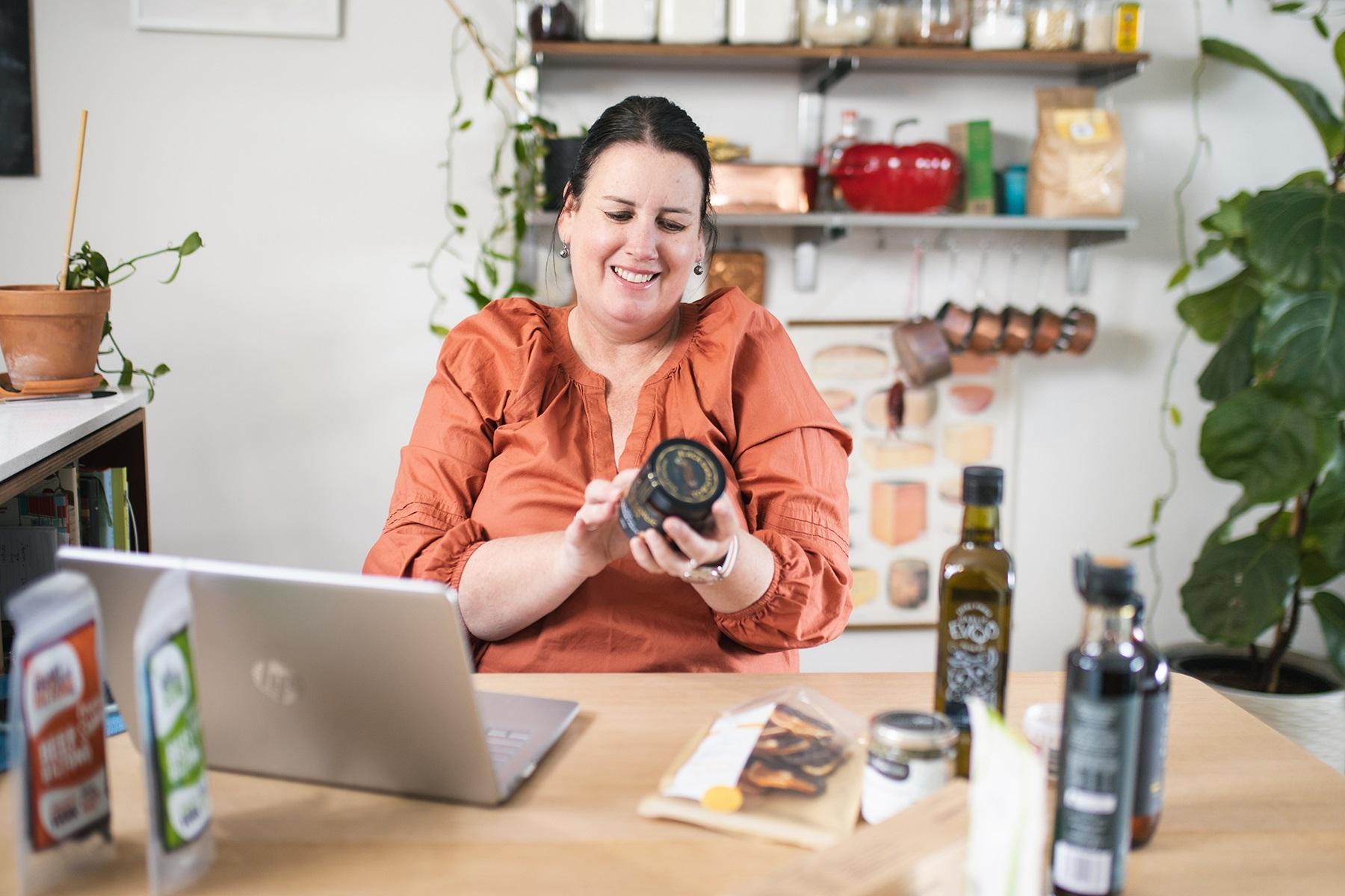 Photo of a female business owner looking at the label of a food product she sells in her business.