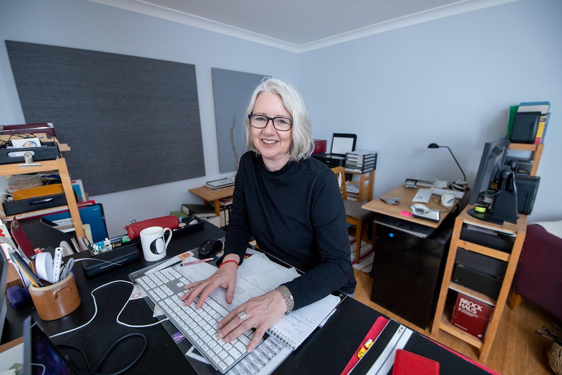 Photo of a woman working on a computer in a home office.