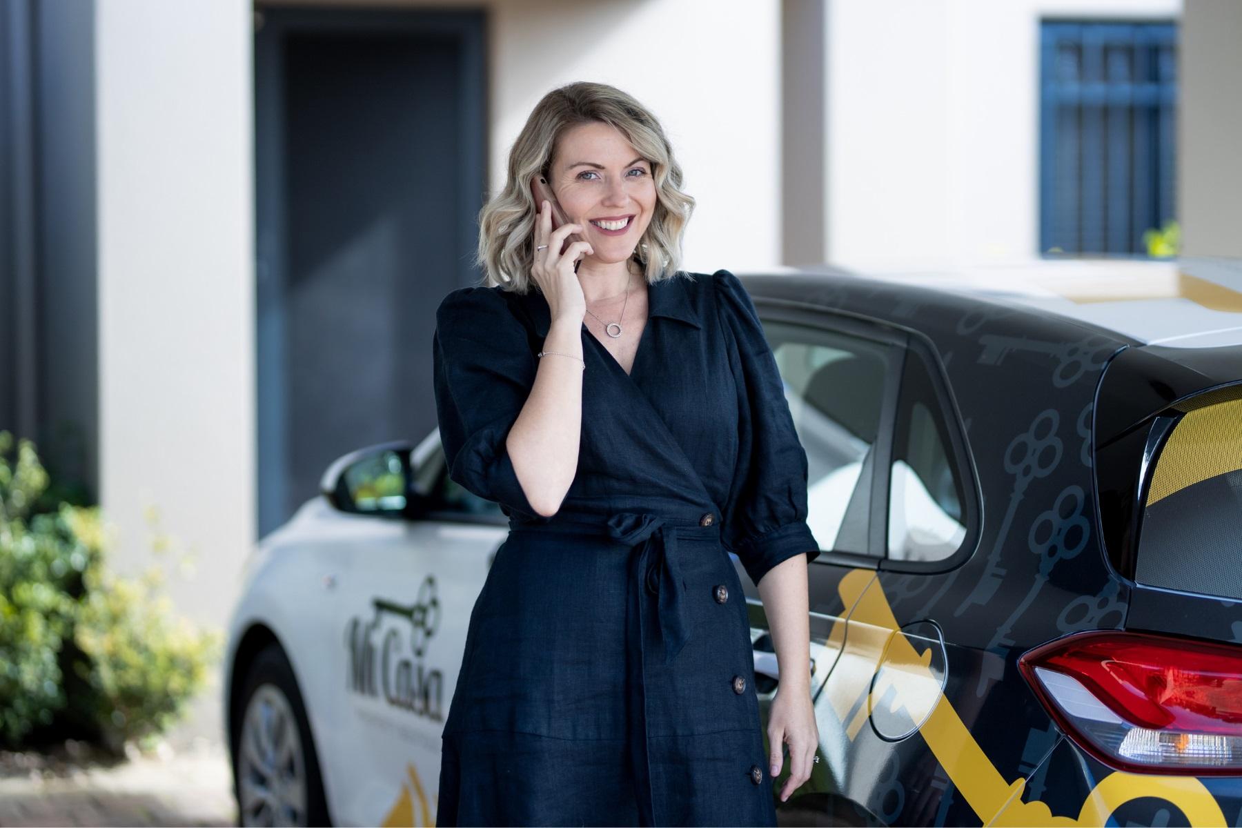 Lady on her phone standing next to a car