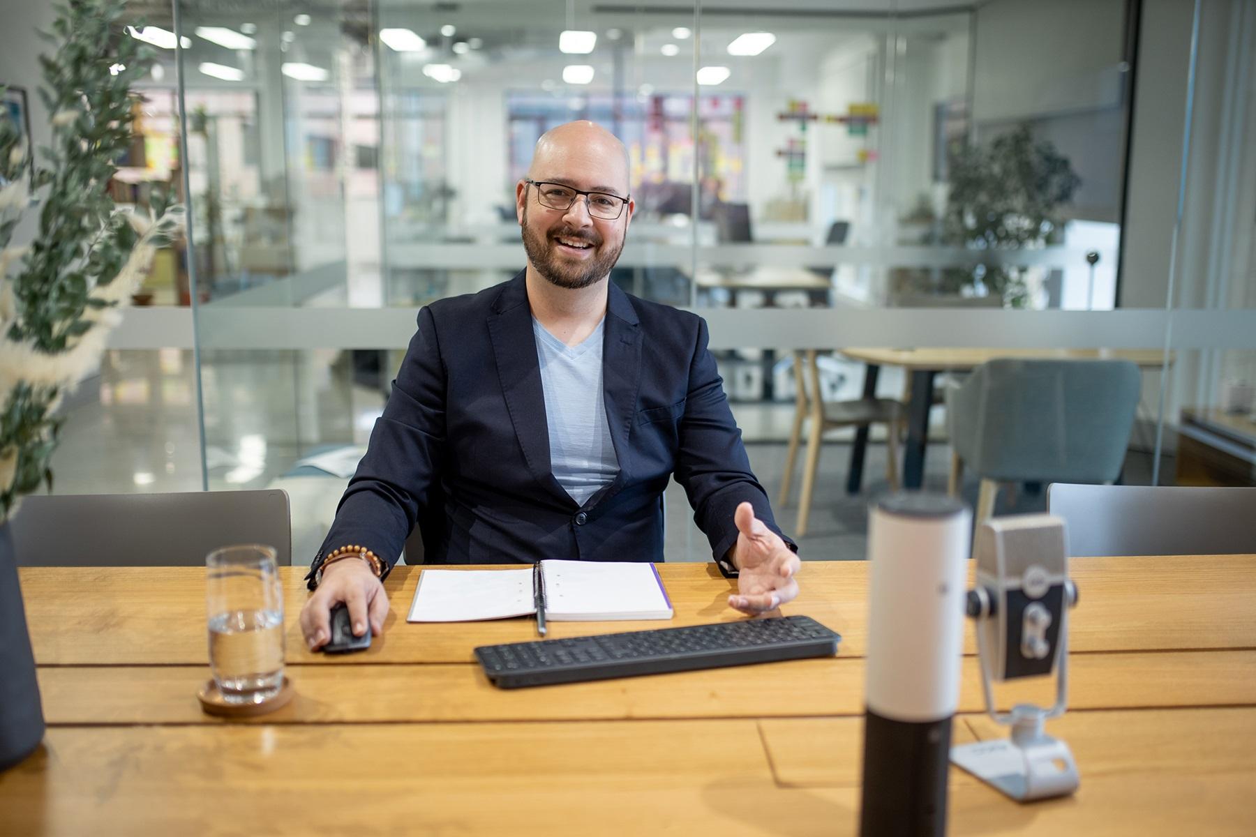 Photo of a man working at a board room table. He is using a wireless keyboard and mouse.