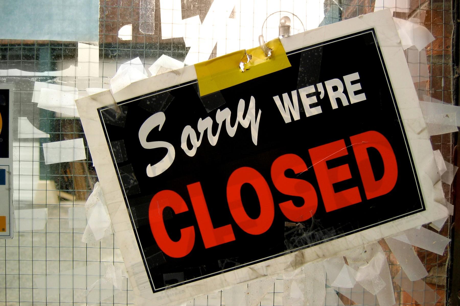 Photo of a 'Sorry we're closed' sign on the window of a business location.