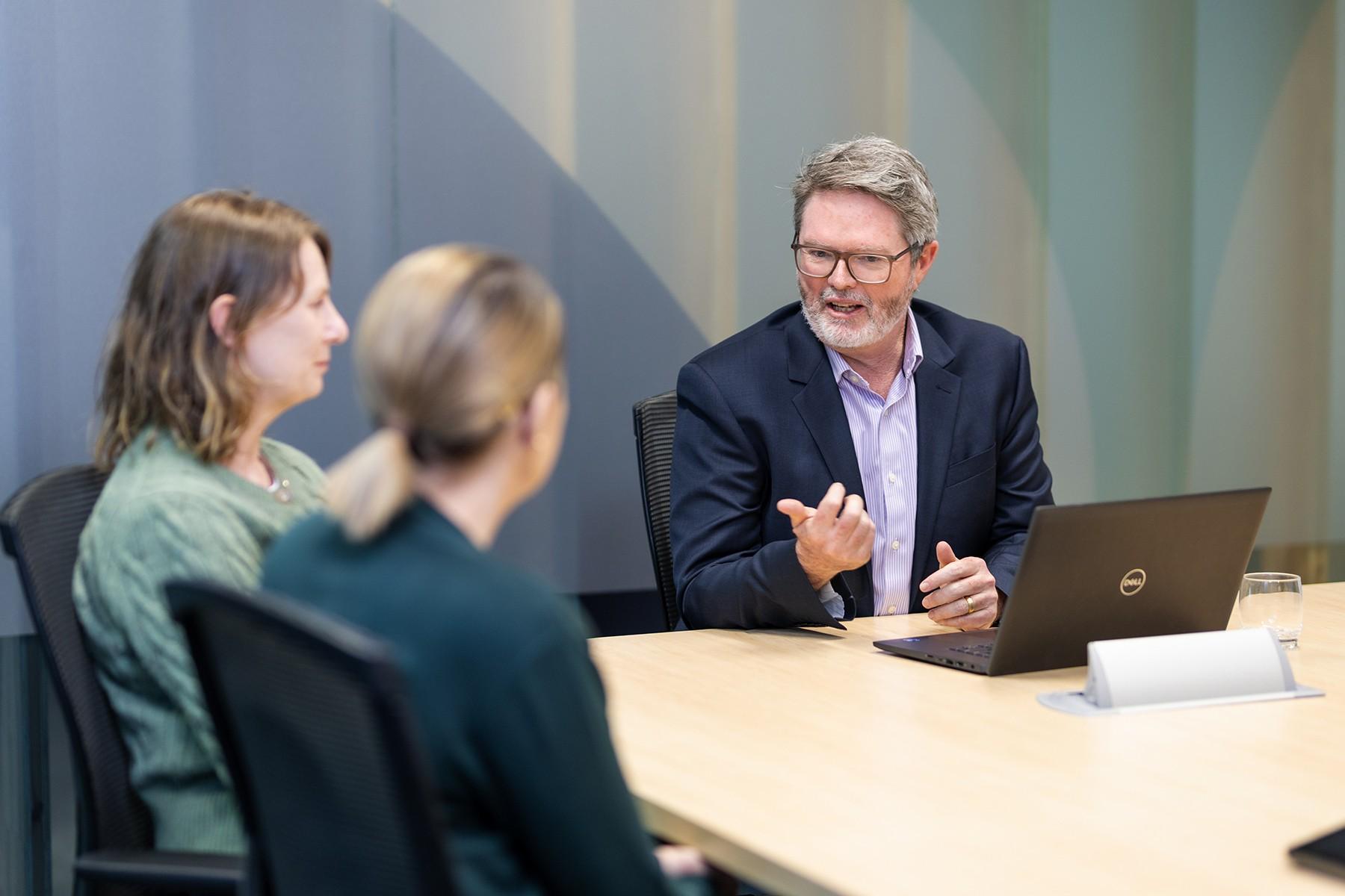 Photo of a male SBDC staff member providing advice to two female clients..