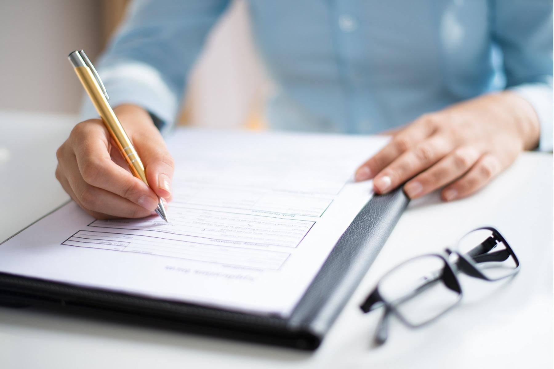 Close up photo of a hand signing a document.