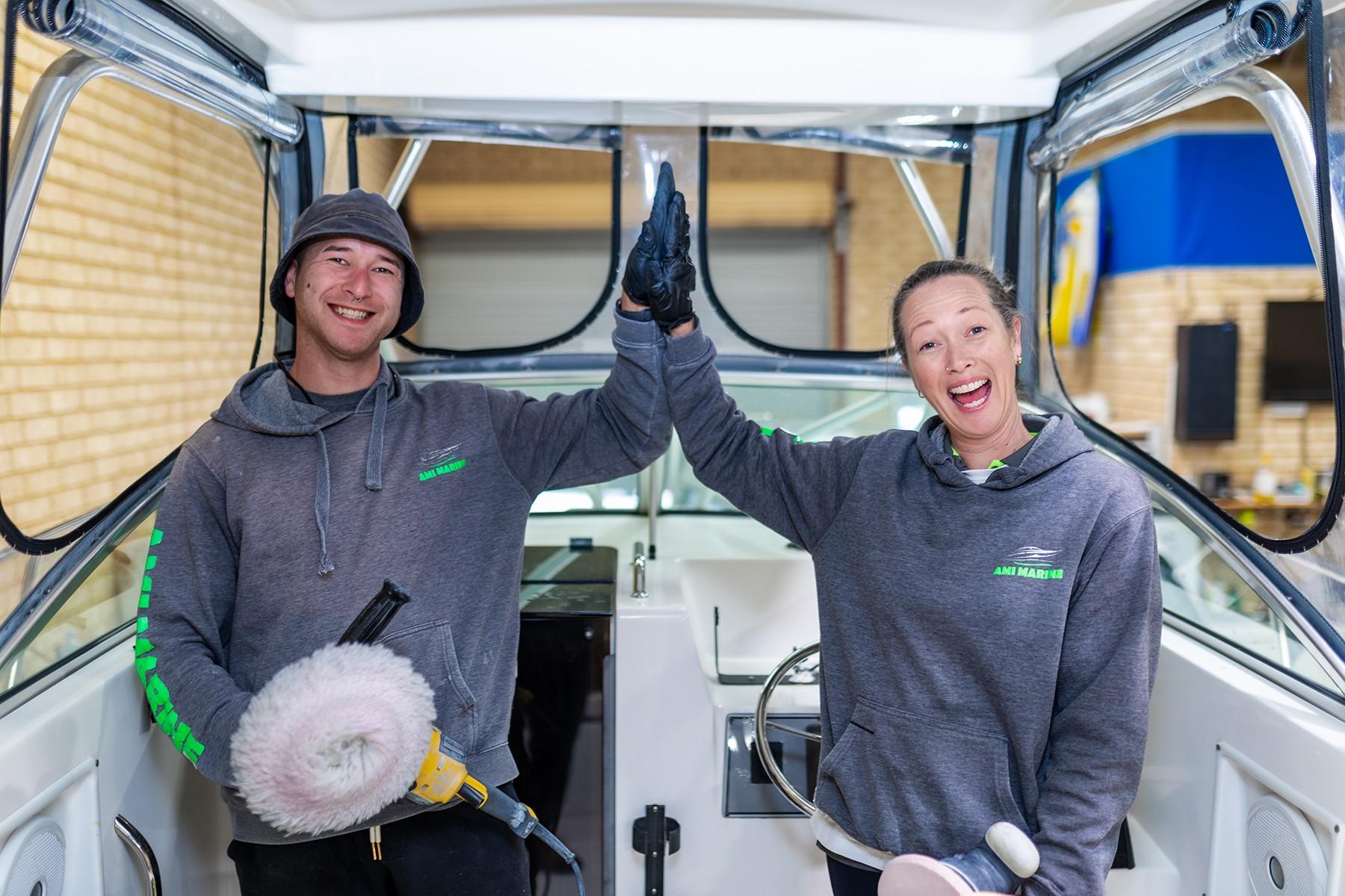 A photo of a man and woman doing a high five as they smile at the camera.