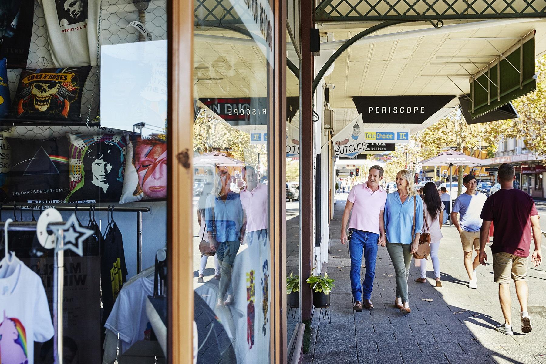 Photo of a retail strip of shops in Perth. There is a man and woman walking on the footpath browsing in the windows of the stores.