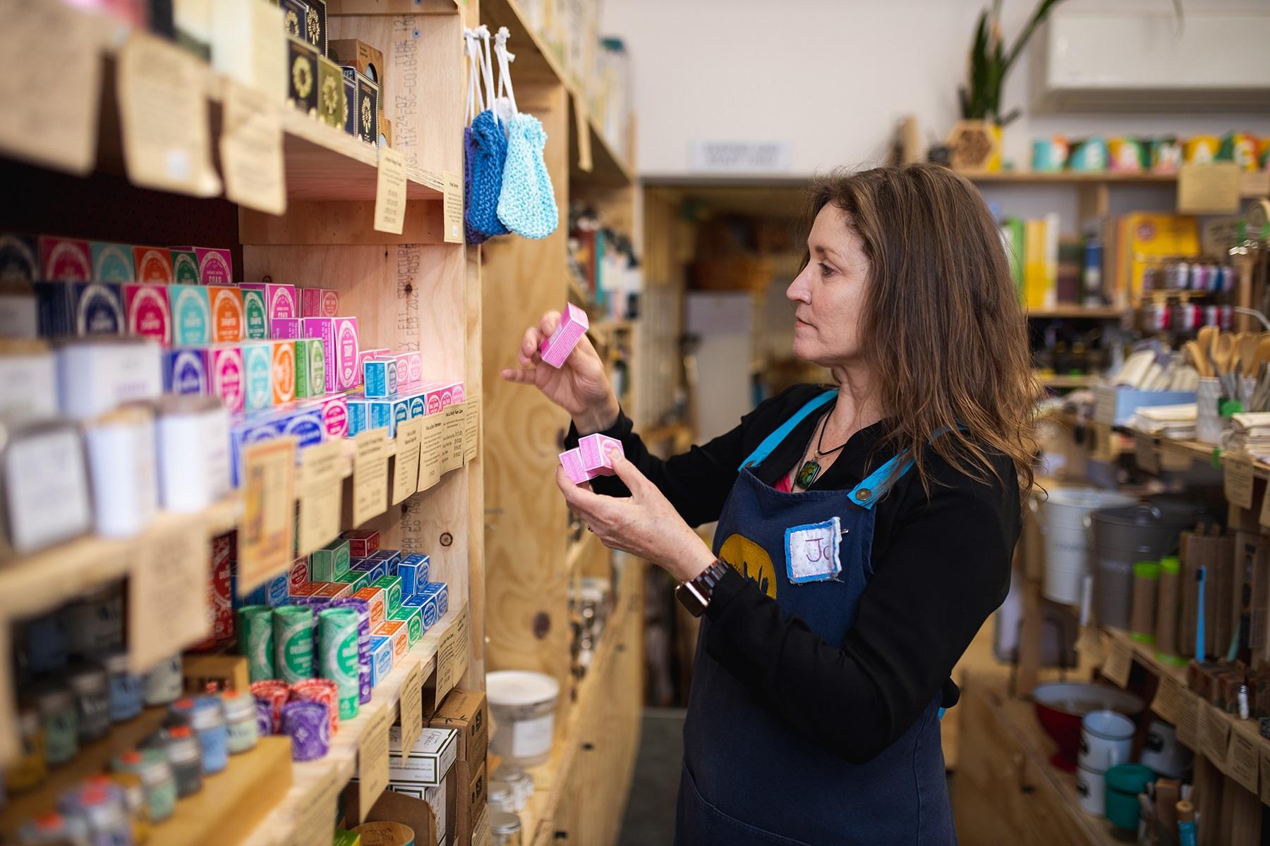 A photo of a female shop owner closely examining at a product from her retail business.