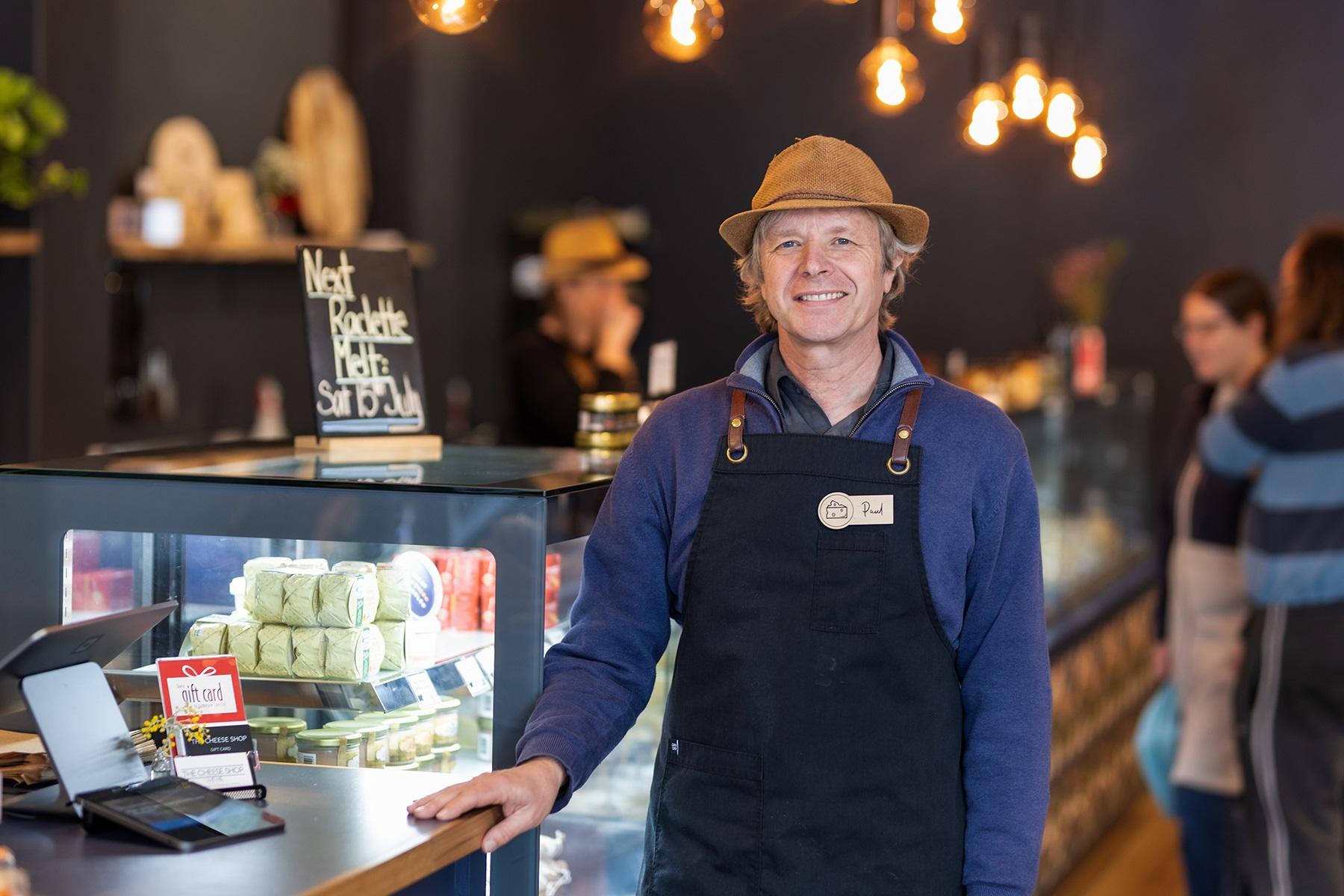 Photo of a male business owner standing at the counter of his food-based business.