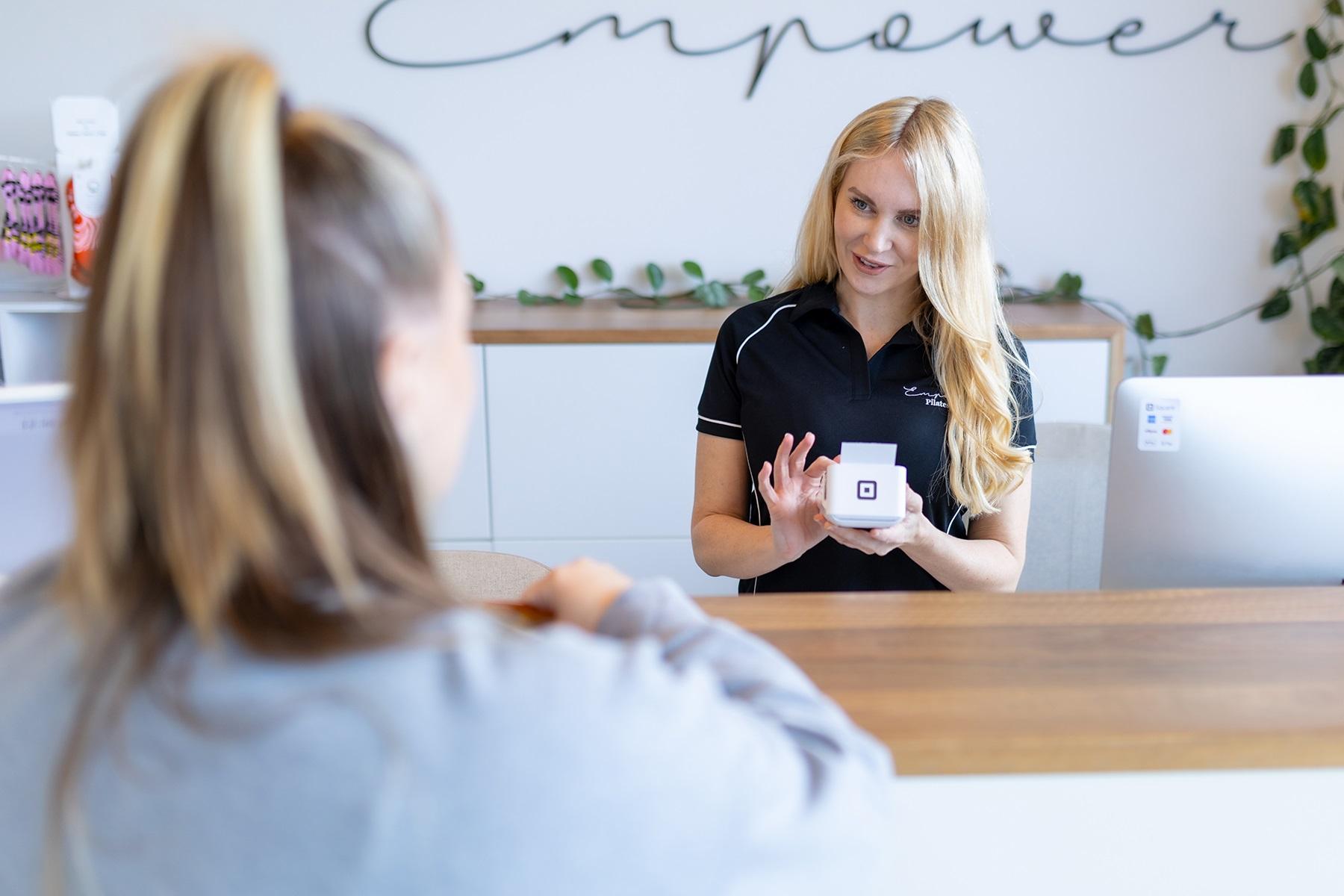 Photo of a female business owner. She is processing a payment on an EFTPOS terminal.