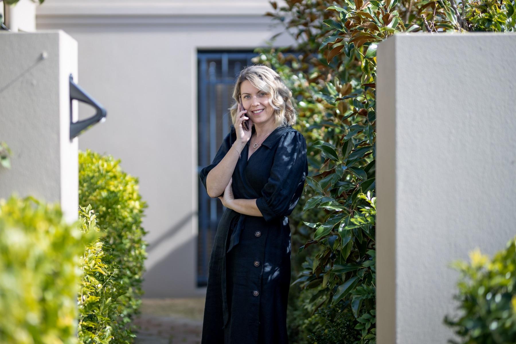 Photo of a real estate agent talking on the phone outside of a residential property.