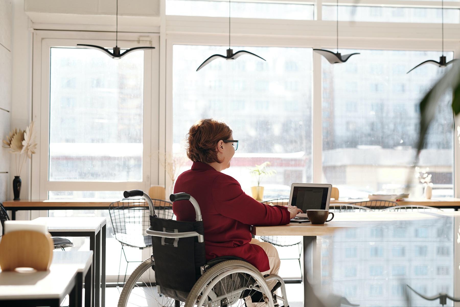 Photo of a woman in a wheelchair working on a laptop.