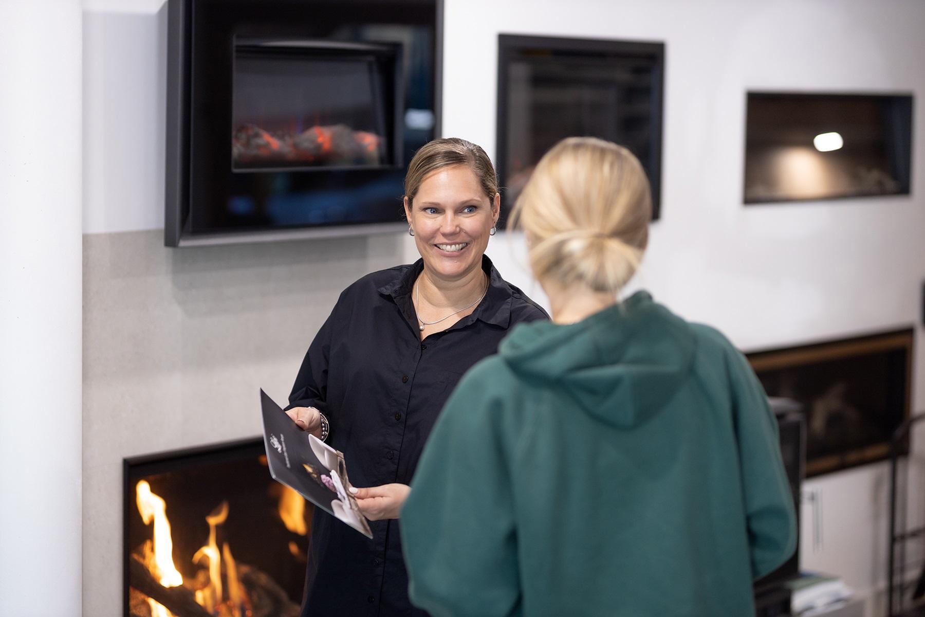 Photo of a female business owner. She is showing a customer a product catalogue.
