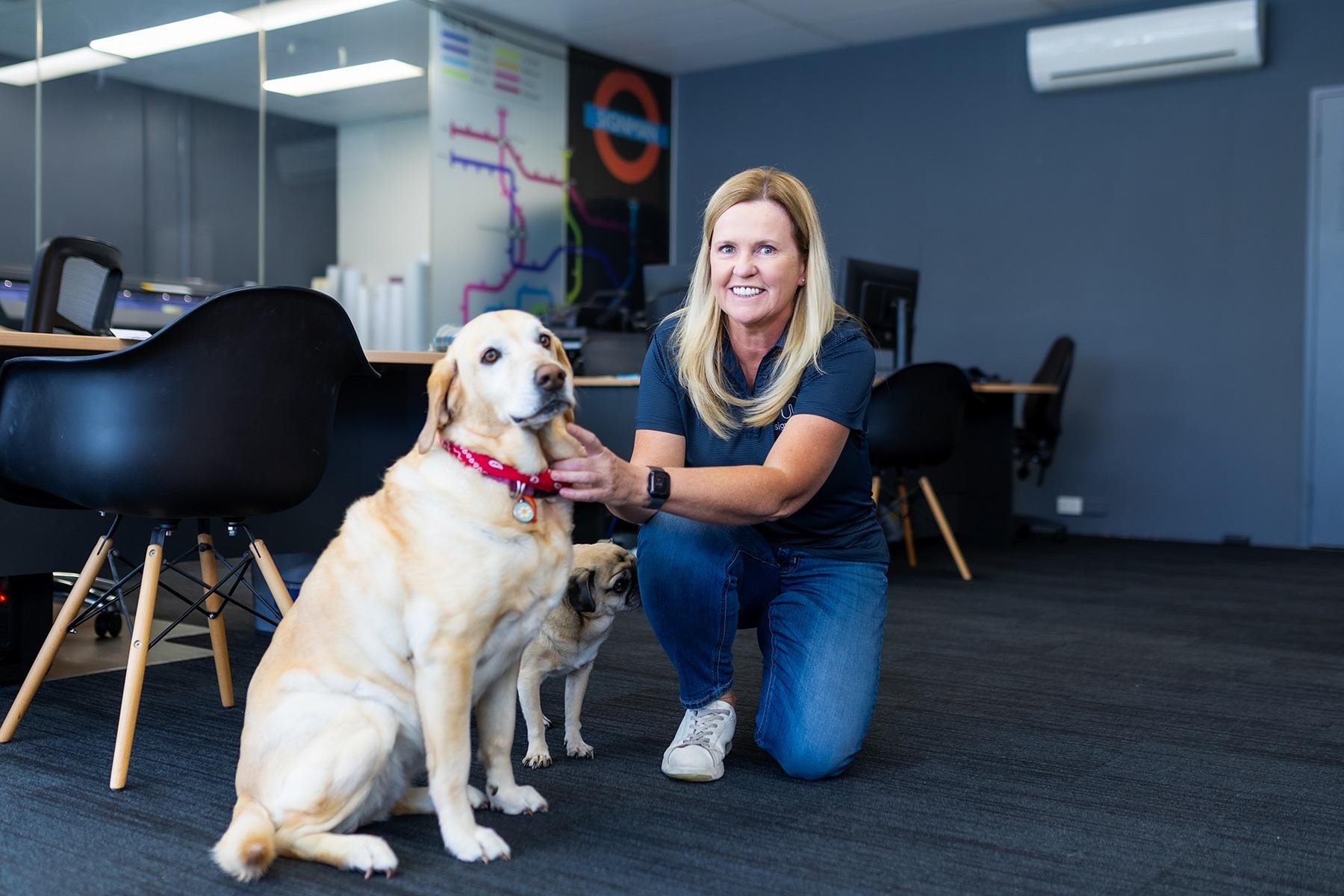 Photo of female business owner. She is in her office with her two pet dogs.