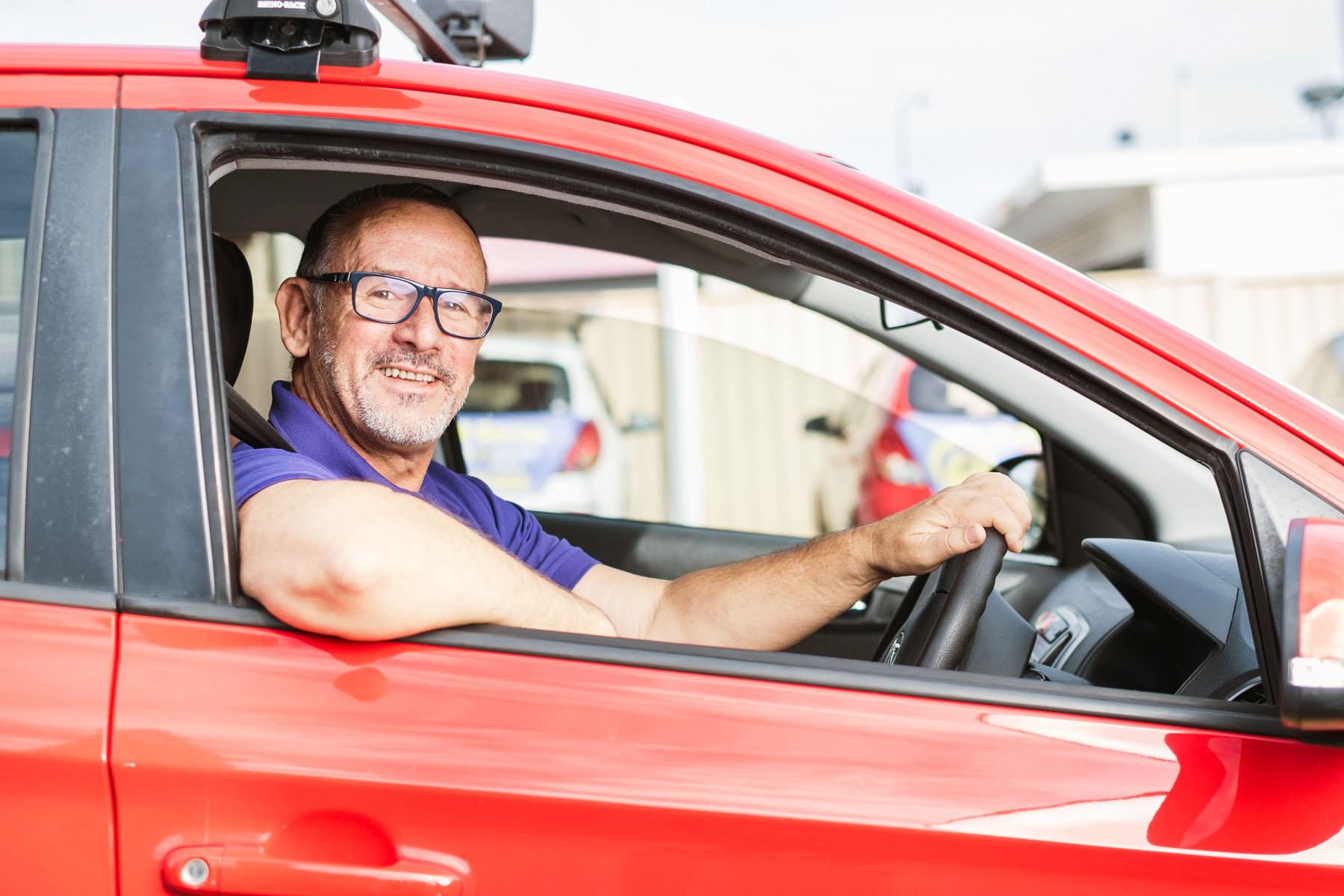 Photo of a small business owner driving a work car.