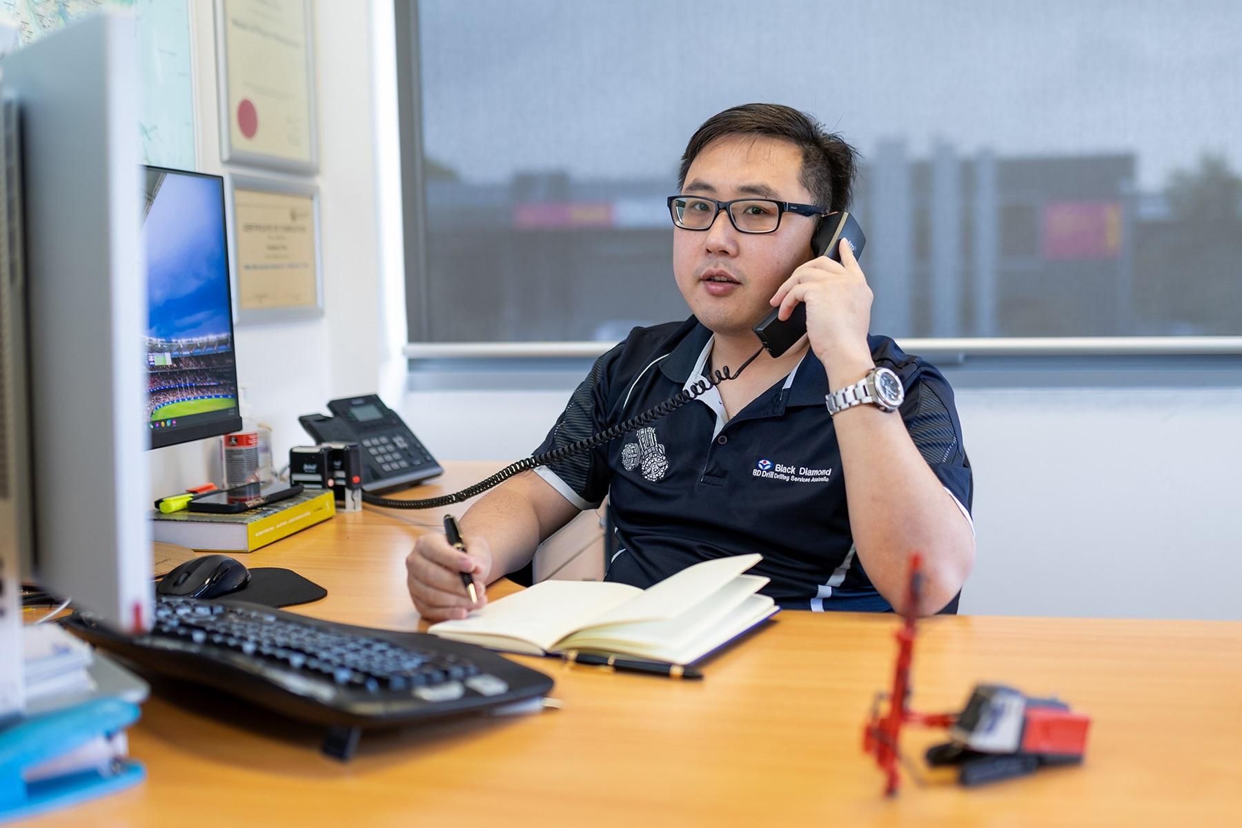 Photo of a male business owner. He is sitting in an office and speaking on the telephone.