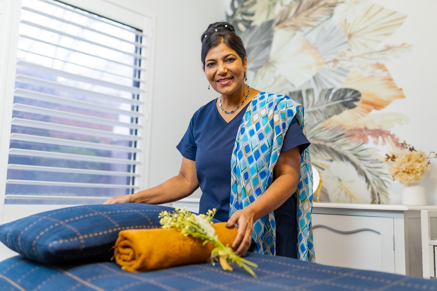 Photo of a female business owner. She is setting up a massage table in her massage and beauty business.