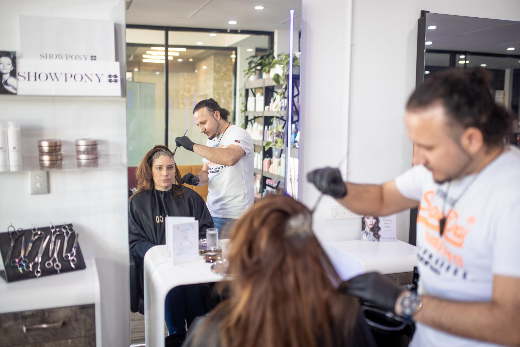 Photo of a male hairdresser applying hair dye to a female customer's head.