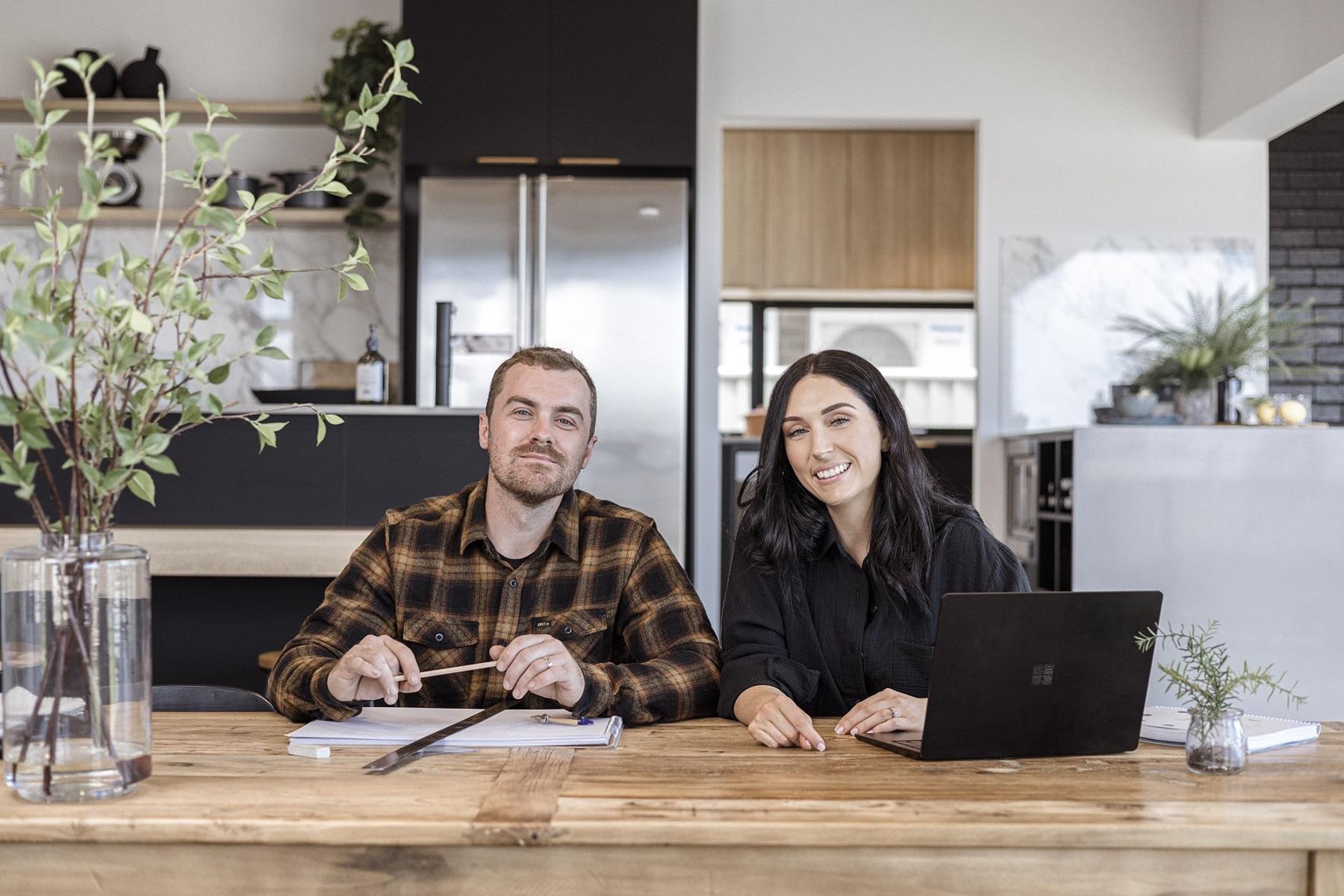 Photo of Cam and Beth Hayes, owners of Empire Copper. They are sitting at a table and smiling at the camera.