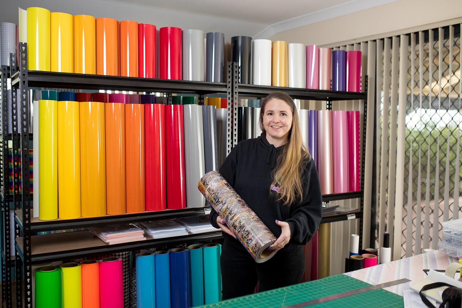 A female business owner holding a roll of vinyl.