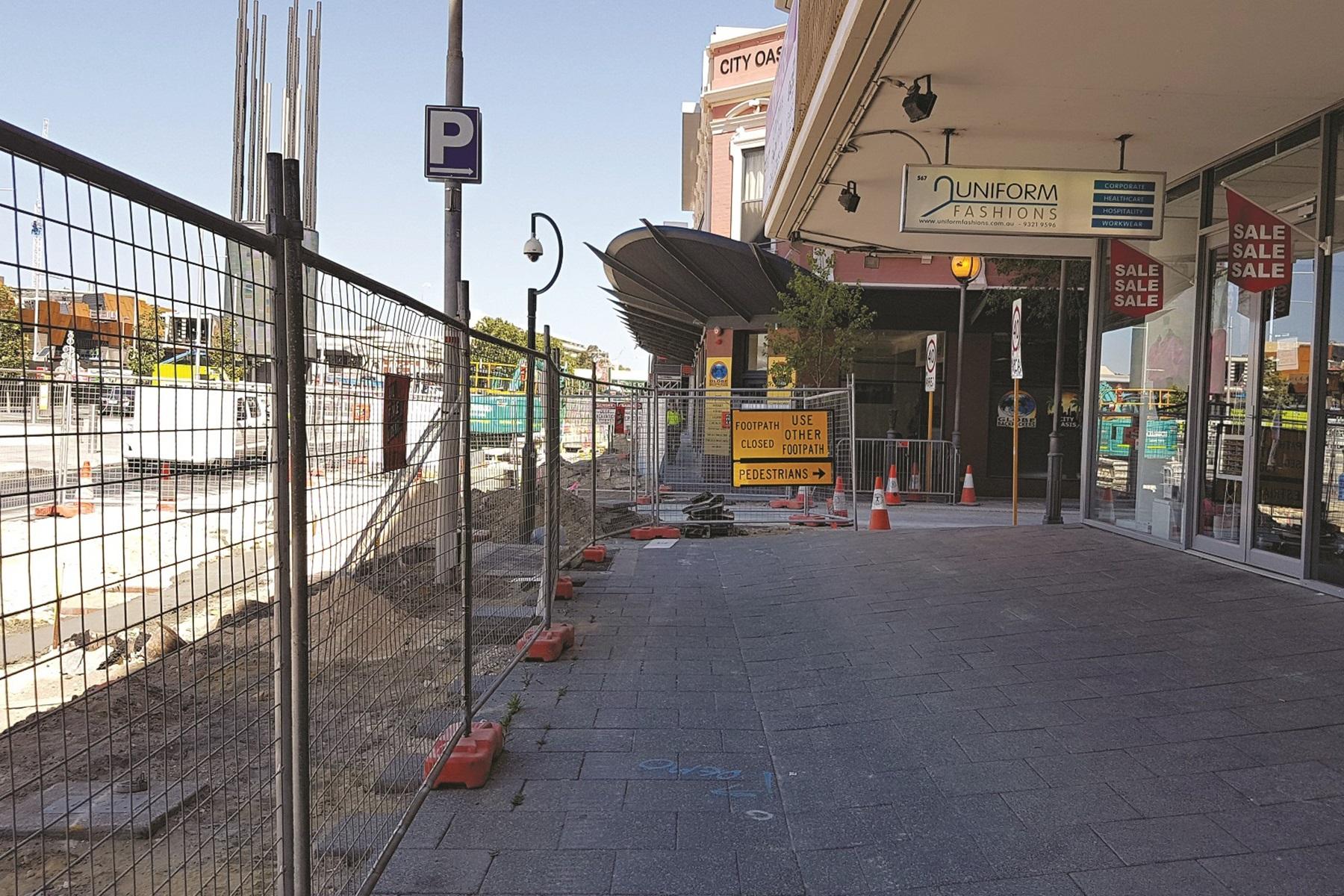 A photo of construction work in the Perth CBD. There is a fence between the footpath and the road and a sign saying the footpath is closed.