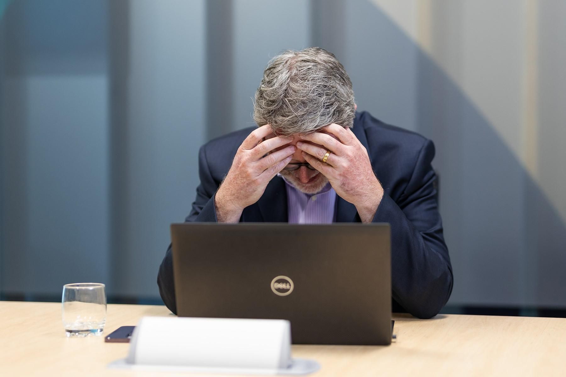 A man sitting at a table with his head in his hands.
