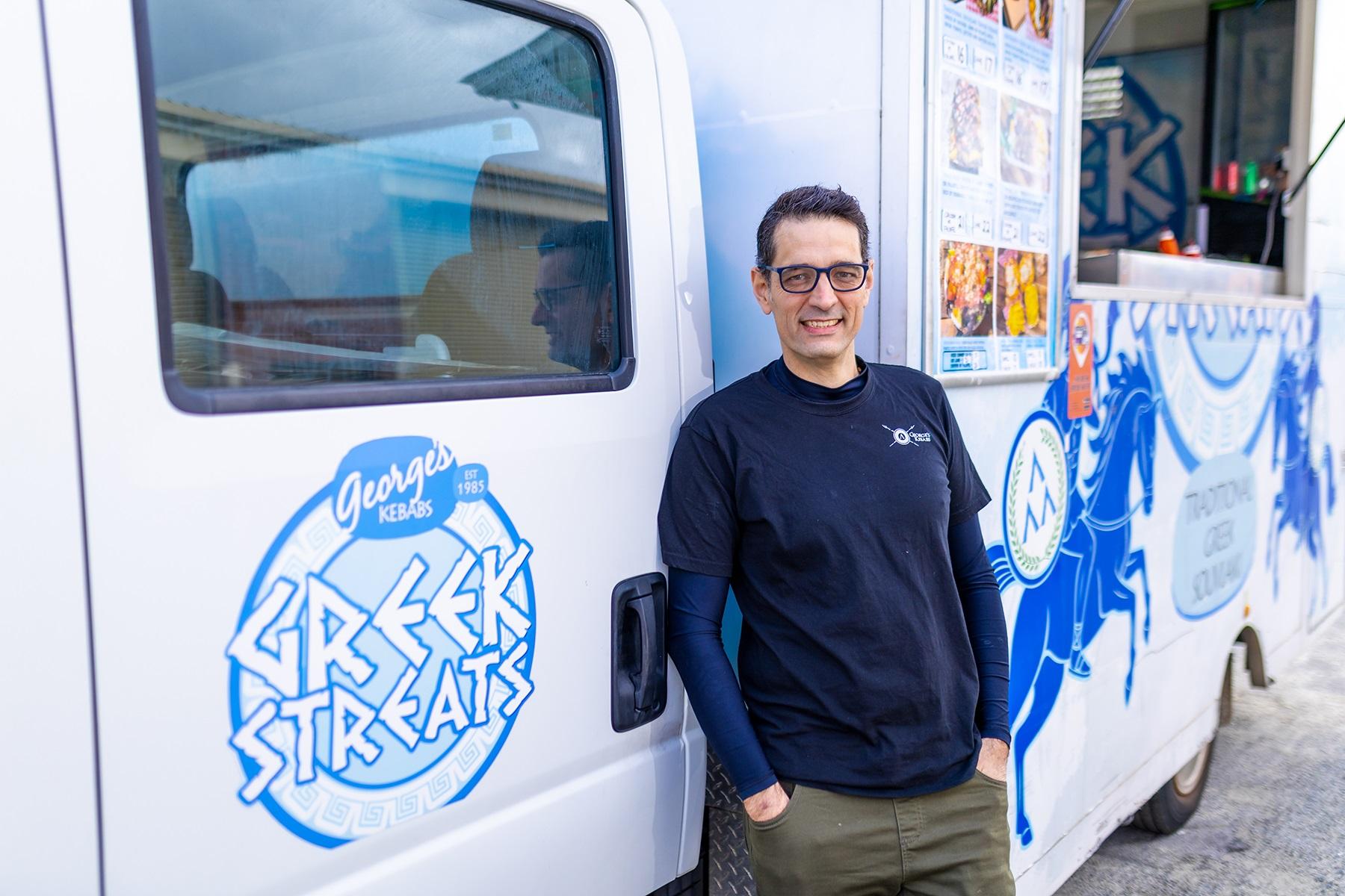 Photo of a male business owner standing in front of his food truck.