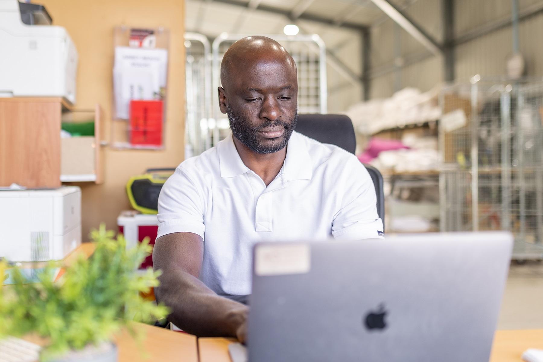 Photo of a male business owner using a laptop in his commercial laundry business.