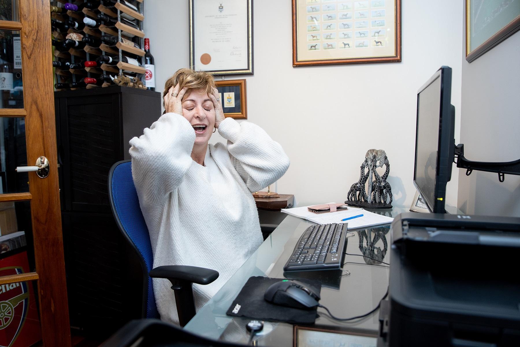 Photo of a female business owner with her hands on her head, looking frustrated.