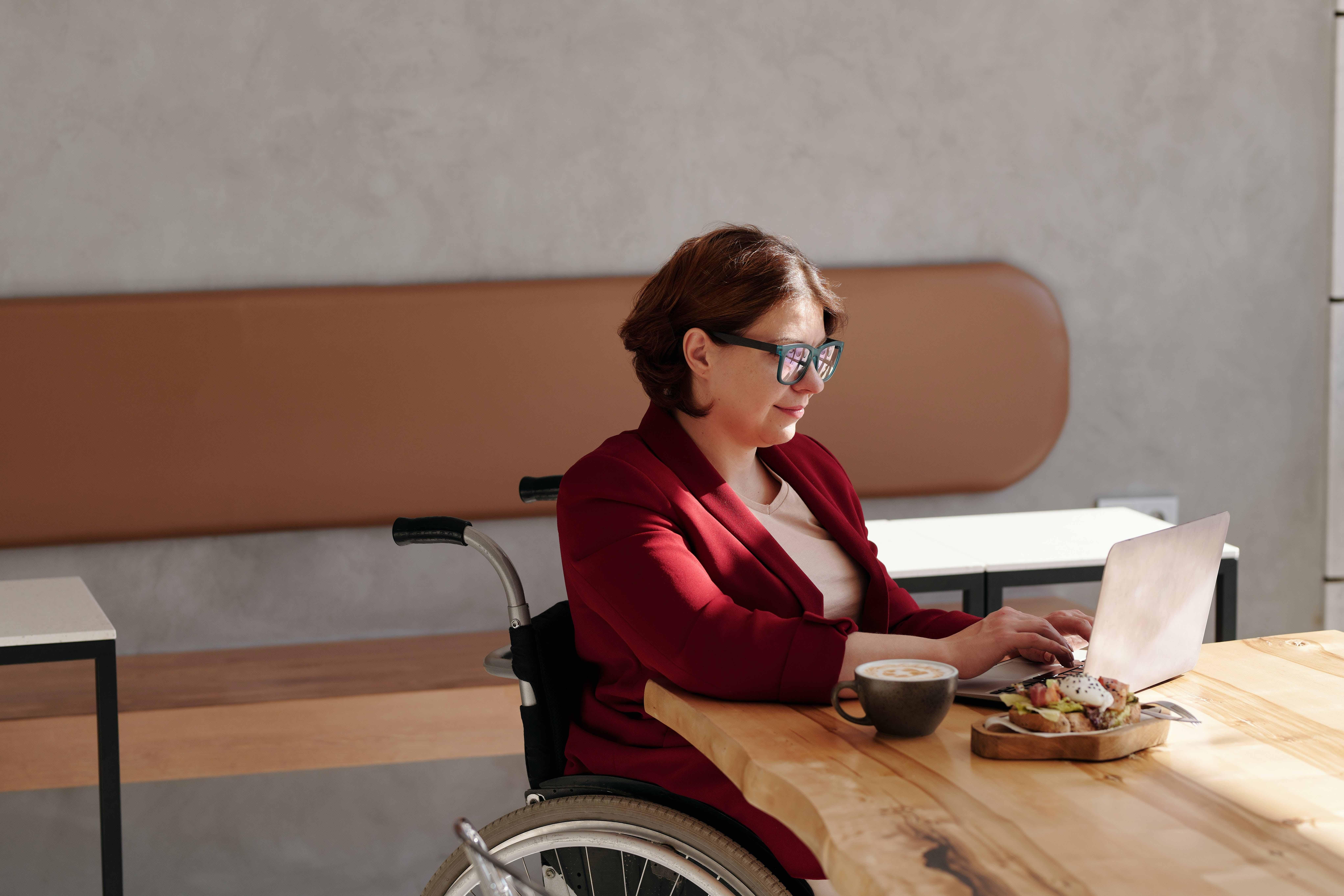 Photo of a woman in a wheelchair working on a laptop.