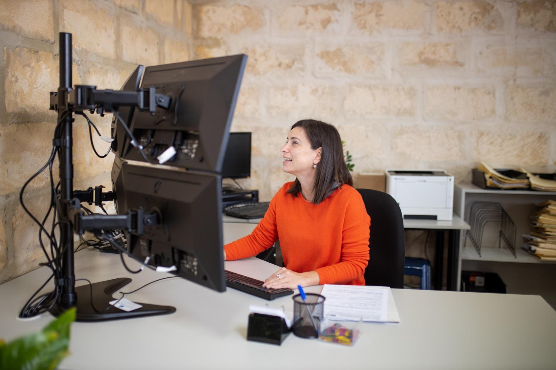 Photo of a woman working at a computer in an office.